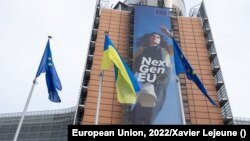 Bendera nasional Ukraina dikibarkan bersama bendera Uni Eropa di markas UE di Brussel, Belgia (foto: dok). 