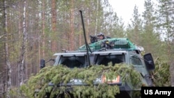 FILE - A Finnish soldier enjoys a moment of reprieve from simulated combat during Exercise Arrow 22, May 5, 2022. 