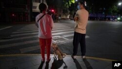Residents walk their dog on a quiet street on the eve of the lifting of a COVID-19 lockdown, May 31, 2022, in Shanghai. Shanghai authorities say they will take major steps Wednesday toward reopening China's largest city after a two-month COVID-19