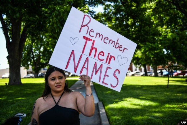 Seorang warga setempat memegang plakat bertuliskan Doa 4 Uvalde saat mereka berduka atas korban penembakan massal di Sekolah Dasar Robb di Uvalde, Texas, pada 25 Mei 2022. (Foto: AFP)