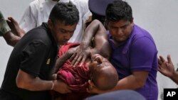 A Sri Lankan Buddhist monk is carried after being injured during protests outside prime minister Mahinda Rajapaksa's residence in Colombo, Sri Lanka, May 9, 2022.