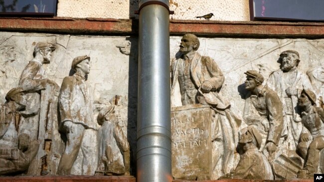 A bird stands on a bas-relief of the Soviet era