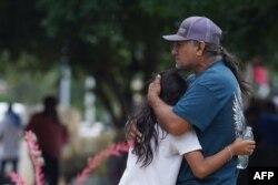 Las familias se abrazan frente al Centro Cívico Willie de Leon, donde se ofrecerá asesoramiento de duelo en Uvalde, Texas, el 24 de mayo de 2022. [Foto: AFP]