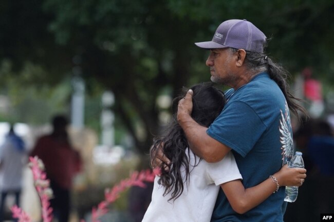 Las familias se abrazan frente al Centro Cívico Willie de Leon, donde se ofrecerá asesoramiento de duelo en Uvalde, Texas, el 24 de mayo de 2022. [Foto: AFP]