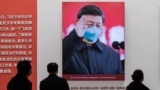 In this picture taken on January 15, 2021, a picture of China's President Xi Jinping with a face mask is displayed as people visit an exhibition about China's fight against the COVID-19 coronavirus.