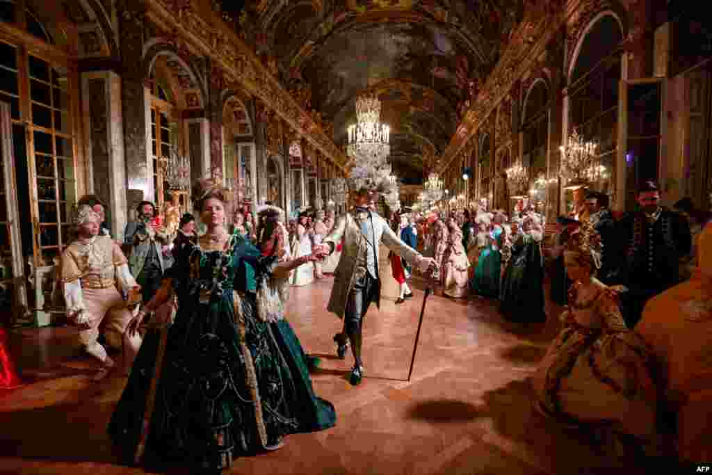 Guests wearing baroque style costumes walk in the Hall of Mirrors at the Chateau de Versailles Palace as part of the sixth edition&#39;s of the Fetes Galantes fancy dress evening which theme is the Royal Wedding of Marie Antoinette and Louis XVI, in Versailles, France, May 23, 2022.