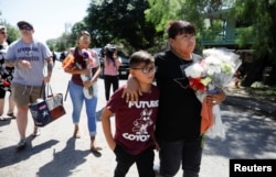 Dora Flores dan cucunya tiba di SD Robb dengan membawa bunga, sehari setelah seorang pria bersenjata membunuh 19 anak dan dua guru di sekolah tersebut di Uvalde, Texas, AS, 25 Mei 2022. (Foto: REUTERS/Marco Bello)