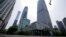 Una mujer con una mascarilla para protegerse del coronavirus pedalea en una calle tranquila junto al cerrado World Trade Center de China, izquierda, luego de que se detectara un caso de COVID-19 en el edificio el lunes 9 de mayo de 2022 en Beijing. (Foto 