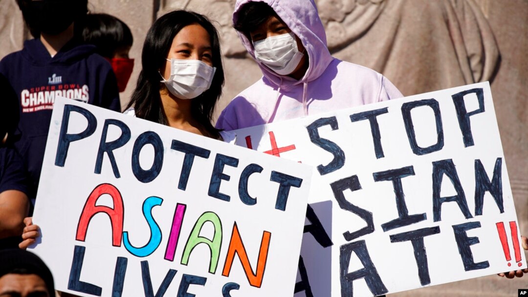 FILE - This March 20, 2021, file photo shows people holding signs as they attend a rally to support Stop Asian Hate at the Logan Square Monument in Chicago.