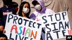 FILE - This March 20, 2021, file photo shows people holding signs as they attend a rally to support Stop Asian Hate at the Logan Square Monument in Chicago.