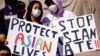 FILE - This March 20, 2021, photo shows people holding signs as they attend a rally to support Stop Asian Hate at the Logan Square Monument in Chicago.