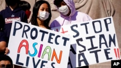 FILE - This March 20, 2021, photo shows people holding signs as they attend a rally to support Stop Asian Hate at the Logan Square Monument in Chicago.