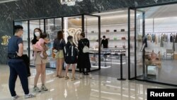 People wearing face masks line up outside a store of French luxury brand Celine, at a reopened shopping mall amid the COVID-19 outbreak in Shanghai, China, May 29, 2022.