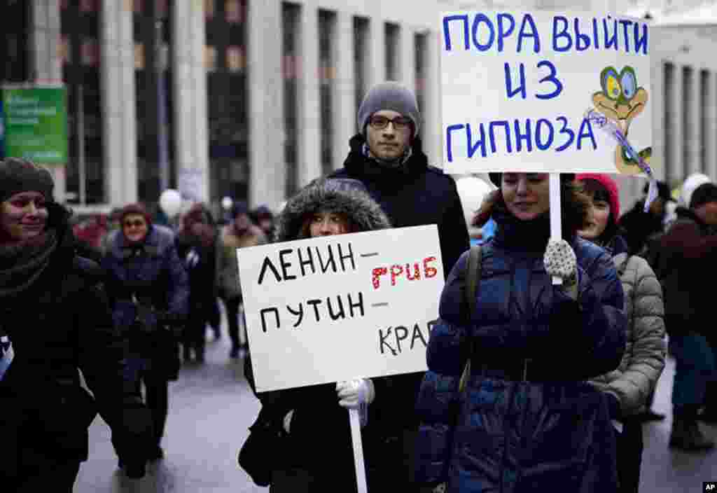 A protester (right) has a sign that reads, "It's time to snap out of your hypnosis." Another protester (left) has a sign that reads, "Lenin is a mushroom. Putin is a crab," December, 2011. (VOA - Y. Weeks)