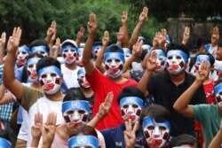 FILE - Young demonstrators flash the three-fingered symbol of resistance during an anti-coup mask strike in Yangon, Myanmar, April 4, 2021.