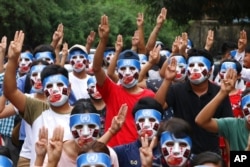 FILE - Young demonstrators flash the three-fingered symbol of resistance during an anti-coup mask strike in Yangon, Myanmar, April 4, 2021.