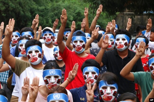 FILE - Young demonstrators flash the three-fingered symbol of resistance during an anti-coup mask strike in Yangon, Myanmar, April 4, 2021.