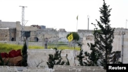 FILE - A Hezbollah flag flutters in a government-controlled area, as seen from the rebel-controlled area of Karm al-Tarab, near Aleppo's airport, April 22, 2015. 