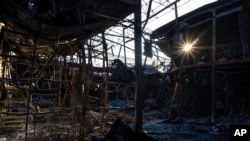 Rayos de sol atraviesan estructuras calcinadas en una zona bombardeada del mercado de Barabashovo, en Járkiv, en el este de Ucrania, el lunes 23 de mayo de 2022. 