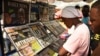 FILE - People read newspaper headlines at a news stand in Dar es Salaam, Tanzania, March 18, 2021.