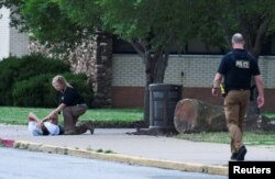 Policajac tješi osobu na lokaciji porodičnog okupljanja, Memorijalnoj srednjoj školi, nakon pucnjave u kampusu bolnice Saint Francis, u Tulsi, Oklahoma, 1. juna 2022. REUTERS/Michael Noble Jr.