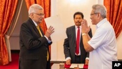 In this handout photograph provided by the Sri Lankan President's Office, President Gotabaya Rajapaksa, right, greets Ranil Wickremesinghe during the latter's oath taking ceremony as the new prime minister, in Colombo, Sri Lanka, May 12, 2022.