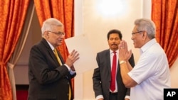 In this handout photograph provided by the Sri Lankan President's Office, President Gotabaya Rajapaksa, right, greets Ranil Wickremesinghe during the latter's oath taking ceremony as the new prime minister, in Colombo, Sri Lanka, May 12, 2022.