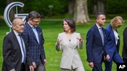German Foreign Minister Annalena Baerbock (C) talks to her Ukrainian counterpart Dmytro Kuleba (2nd L) as they and other participants of a G-7 ministerial walk on the grounds of Weissenhaus Castle at Weissenhaeuser Strand, Germany, May 13, 2022.