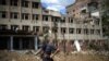 Un residente de pie junto a un edificio muy dañado en un bombardeo ruso enfrente de su casa en Bakhmut, en el este de Ucrania, el martes 24 de mayo de 2022. (AP Foto/Francisco Seco)