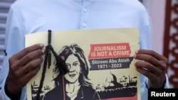 FILE - A journalist holds a placard with a picture of Al Jazeera reporter Shireen Abu Akleh, who was killed during an Israeli raid in the occupied West Bank area of Jenin, during a protest in Mogadishu, Somalia, May 13, 2022.