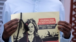 FILE - A journalist holds a placard with a picture of Al Jazeera reporter Shireen Abu Akleh, who was killed during an Israeli raid in the occupied West Bank area of Jenin, during a protest in Mogadishu, Somalia, May 13, 2022.