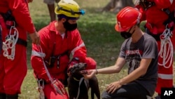 Members of the Red Cross play with a dog rescued from the rubble at the site of a deadly explosion that destroyed the five-star Hotel Saratoga in Old Havana, Cuba, May 8, 2022. 