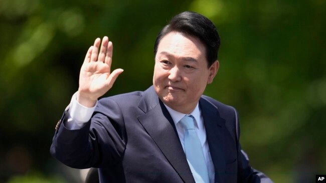 South Korea's new President Yoon Suk Yeol waves from a car after the Presidential Inauguration outside the National Assembly in Seoul, South Korea, Tuesday, May 10, 2022. (AP Photo/Lee Jin-man)