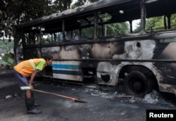 A man looks at a damaged bus of Sri Lanka's ruling party supporters after it was set on fire during a clash of pro and anti-government demonstrators near the prime minister's official residence, in Colombo, Sri Lanka, May 10, 2022.