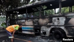 A man looks at a damaged bus of Sri Lanka's ruling party supporters after it was set on fire during a clash of pro and anti-government demonstrators near the Prime Minister's official residence, amid the country's economic crisis, in Colombo, Sri Lanka, M