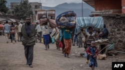 FILE - People attempt to cross the Democratic Republic of Congo and Ugandan border with their belongings to seek refuge after clashes between the Congolese army and the M23, in Bunagana, 100 kilometers from the city of Goma in eastern DRC, on April 2, 202