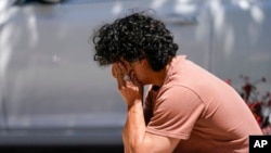 Gabe Kipers, a neighbor of church shooting victim Dr. John Cheng, kneels at a memorial for him outside his office building on May 17, 2022, in Aliso Viejo, Calif.