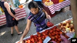 A woman buys tomatoes at a street market in Rio de Janeiro, Brazil, Wednesday, May 11, 2022. (AP Photo/Silvia Izquierdo)