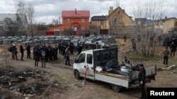 FILE - French forensics investigators, who arrived in Ukraine for the investigation of war crimes amid Russia's invasion, stand next to a mass grave in the town of Bucha, in Kyiv region, Ukraine, Apr. 12, 2022. 