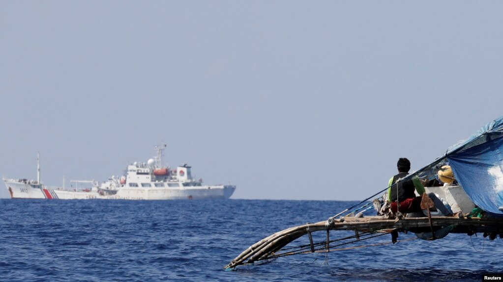 菲律宾渔船上的渔民注视中国的海警船在中国所称的黄岩岛附近有争议海域上巡逻。（资料照 2017年4月5日）(photo:VOA)