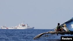 菲律宾渔船上的渔民注视中国的海警船在中国所称的黄岩岛附近有争议海域上巡逻。（资料照 2017年4月5日）