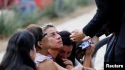 A woman reacts as a priest comforts people outside the Ssgt. Willie de Leon Civic Center, where students had been transported from Robb Elementary School after a shooting, in Uvalde, Texas, May 24, 2022.