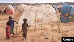 FILE - Children stand next to a makeshift shelter at the Higlo camp for people displaced by drought, in the town of Gode, in Ethiopia's Somali region, April 27, 2022. 