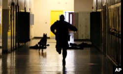 In this April 11, 2010 photo, Detroit Public Schools K9 officer John Greene and his dog Nitro run through a hallway. (AP Photo/Carlos Osorio)