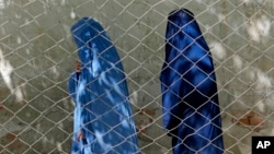 FILE - Two women head a government office, in Kabul, Afghanistan, April 27, 2022. Afghanistan's Taliban leadership has ordered all Afghan women to wear the all-covering burqa in public.