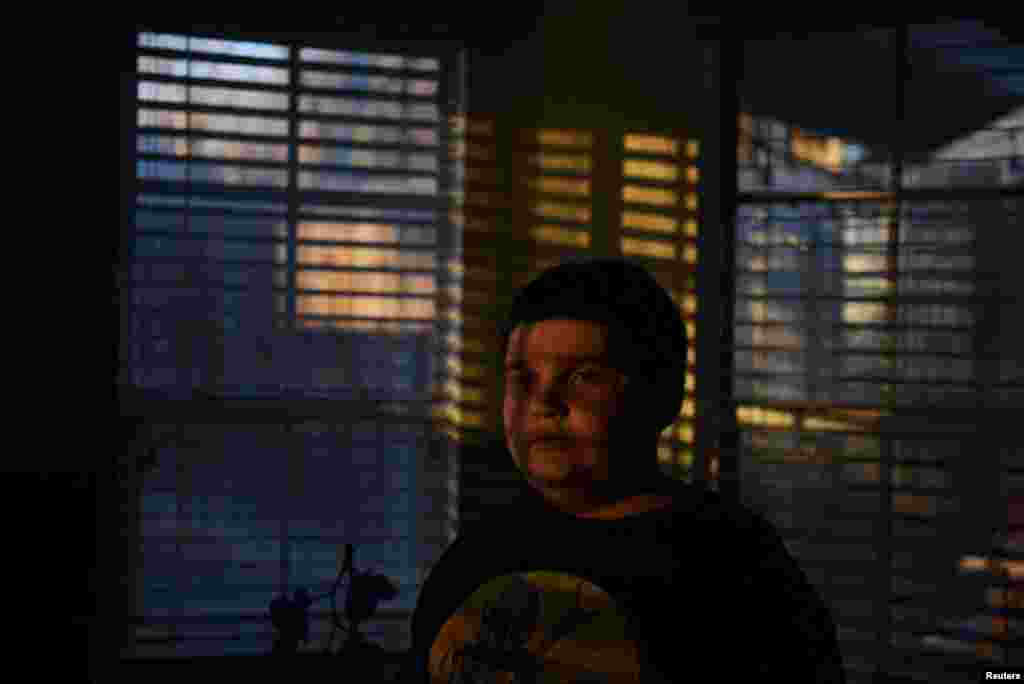 Aidan Garza, 12, poses for a portrait at home in Converse, Texas, Feb. 27, 2022. Aidan Garza often talks about his dad in the present tense, as if David Garza were still right across the living room, sitting in his favorite chair, calling the 12-year-old over to watch a Star Wars series. As if he had never collapsed while out running errands on Dec. 30, 2020, in Converse, Texas. As if he had never died of COVID, one of the now 1 million Americans to succumb to the pandemic. "He's such a warm guy," says Aidan. "Every time I would hug him, I feel like I'm touching a cloud."