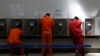 Unos detenidos hablan por teléfono en el centro de detención del Servicio de Control de Inmigración y Aduanas de Estados Unidos en Adelanto, California.