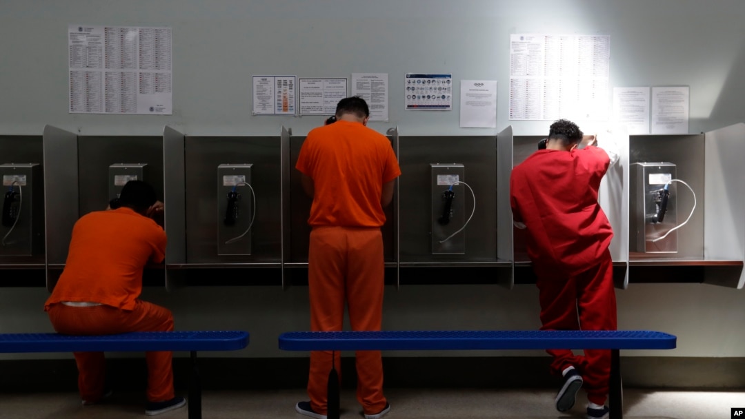 Unos detenidos hablan por teléfono en el centro de detención del Servicio de Control de Inmigración y Aduanas de Estados Unidos en Adelanto, California.
