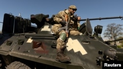 Ukrainian soldiers ride on an armored vehicle en route to the front line, amid Russia's invasion in Ukraine, in Bakhmut in the Donetsk region, May 8, 2022. 