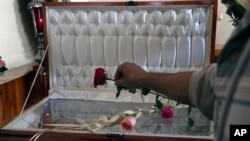 Un amigo coloca una rosa en el ataúd que contiene los restos del periodista asesinado Armando Linares en Zitácuaro, en el estado de Michoacán, México, el 16 de marzo de 2022 